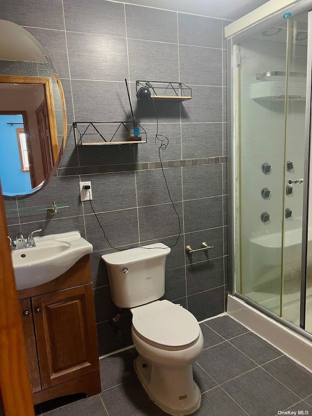 bathroom featuring tile patterned flooring, vanity, toilet, and tile walls