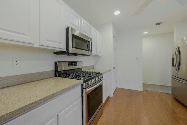 kitchen featuring light stone counters, light hardwood / wood-style flooring, white cabinets, and stainless steel appliances