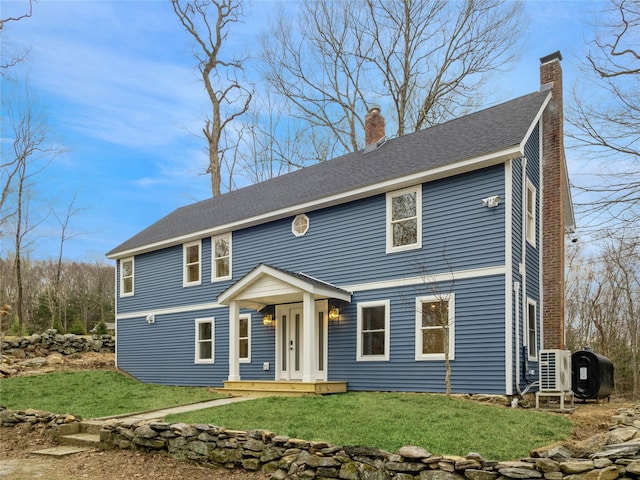 view of front of home featuring a chimney, a front yard, and a shingled roof