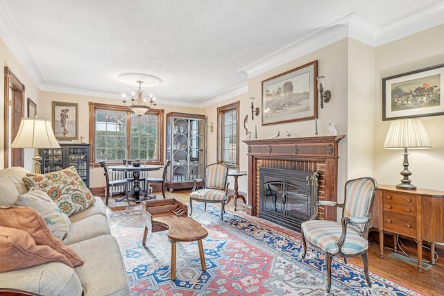 living room with a brick fireplace, hardwood / wood-style floors, an inviting chandelier, and ornamental molding