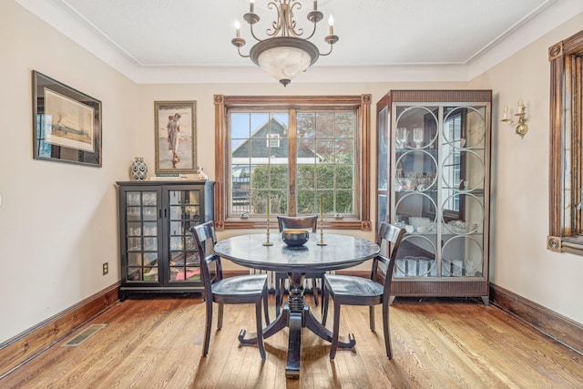 dining room with hardwood / wood-style flooring, a notable chandelier, and ornamental molding