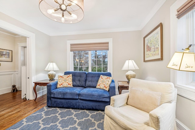 living room with hardwood / wood-style floors, an inviting chandelier, and ornamental molding