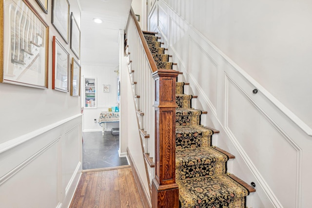 stairs with hardwood / wood-style floors and ornamental molding