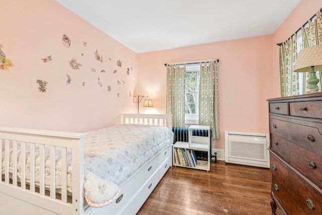 bedroom featuring radiator heating unit and dark hardwood / wood-style flooring