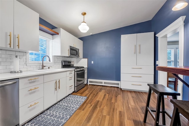 kitchen with white cabinetry, sink, hanging light fixtures, decorative backsplash, and appliances with stainless steel finishes