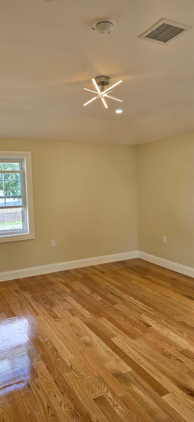 unfurnished room with a notable chandelier and light hardwood / wood-style floors