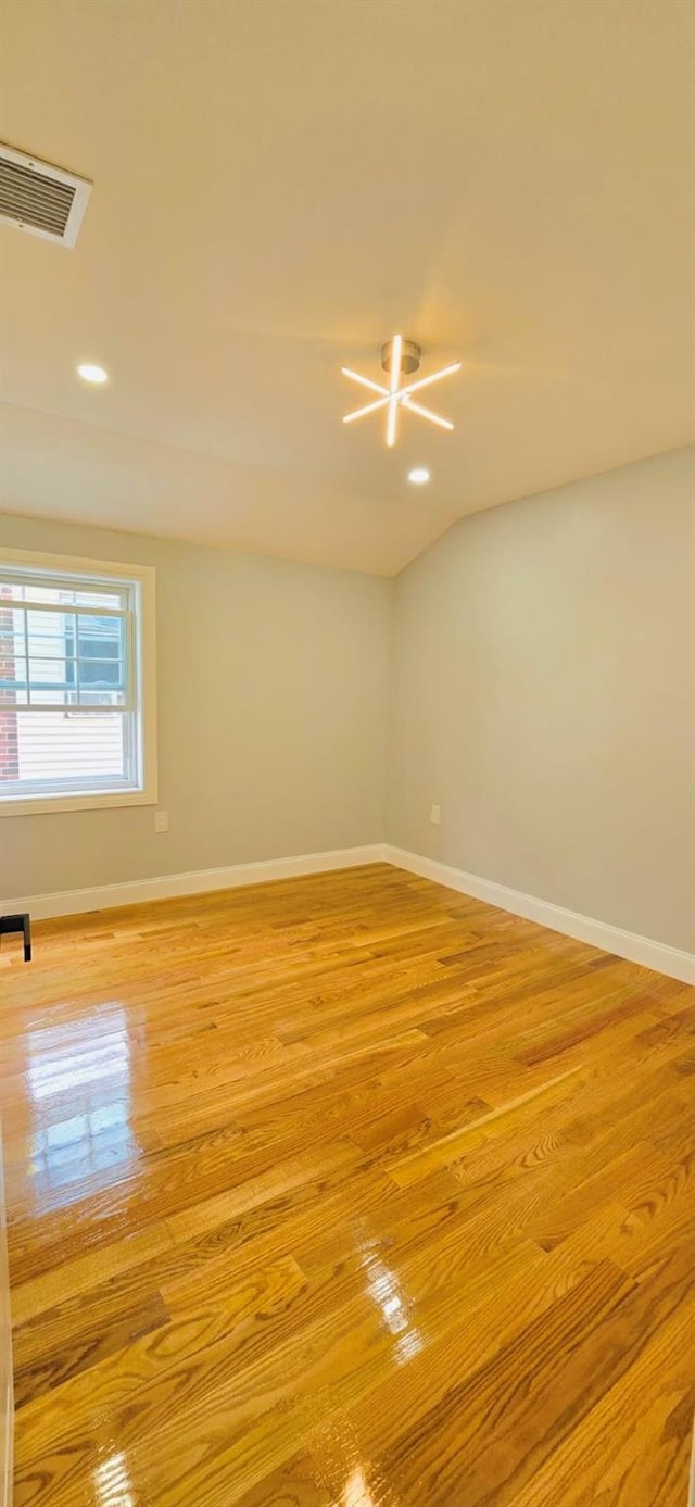 spare room featuring light wood-type flooring and an inviting chandelier