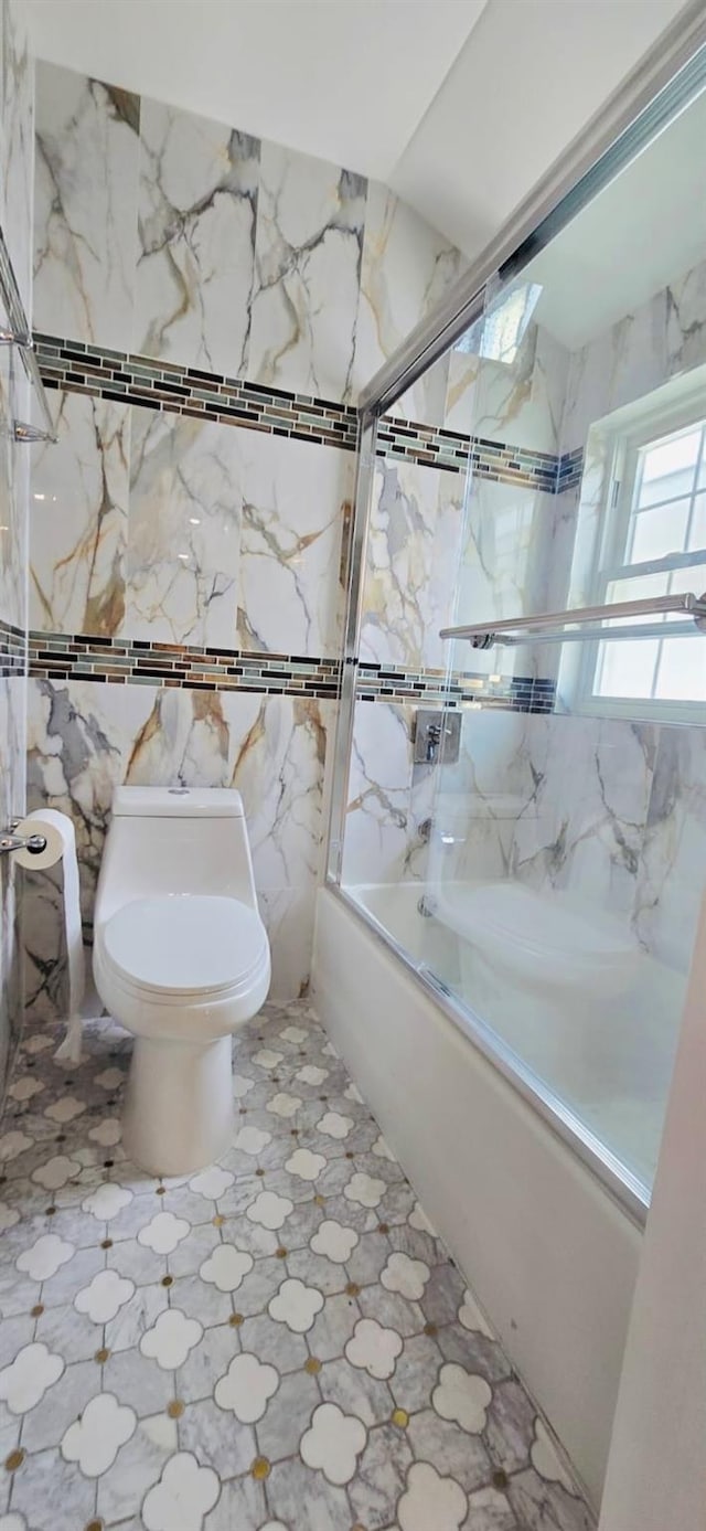 bathroom featuring enclosed tub / shower combo and toilet