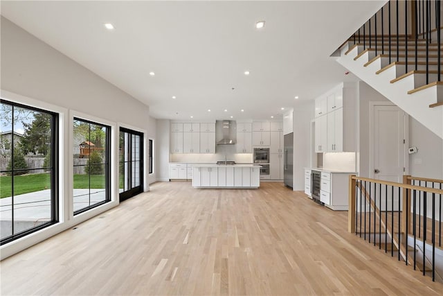 unfurnished living room featuring beverage cooler and light hardwood / wood-style floors