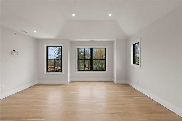 unfurnished room featuring a healthy amount of sunlight, light hardwood / wood-style floors, and lofted ceiling