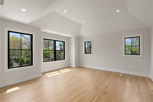 spare room with vaulted ceiling and light hardwood / wood-style flooring