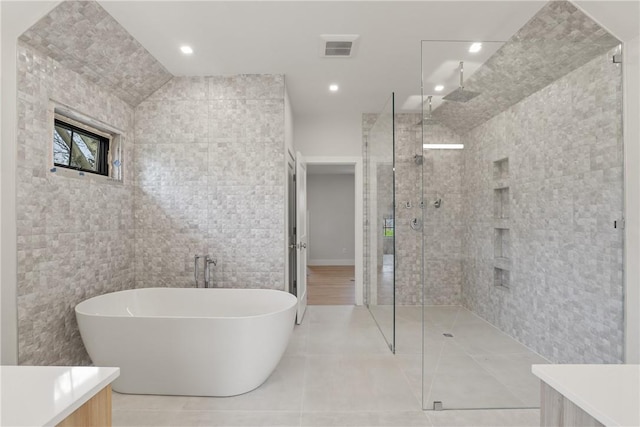 bathroom with tile patterned flooring, shower with separate bathtub, vanity, and tile walls