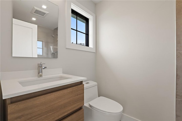 bathroom with walk in shower, vanity, and toilet