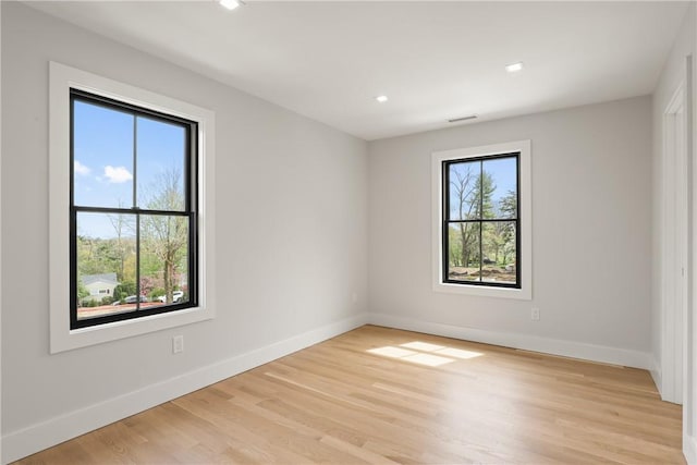 spare room featuring a wealth of natural light and light hardwood / wood-style floors