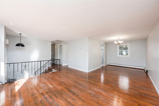 empty room with dark hardwood / wood-style floors, an inviting chandelier, and baseboard heating