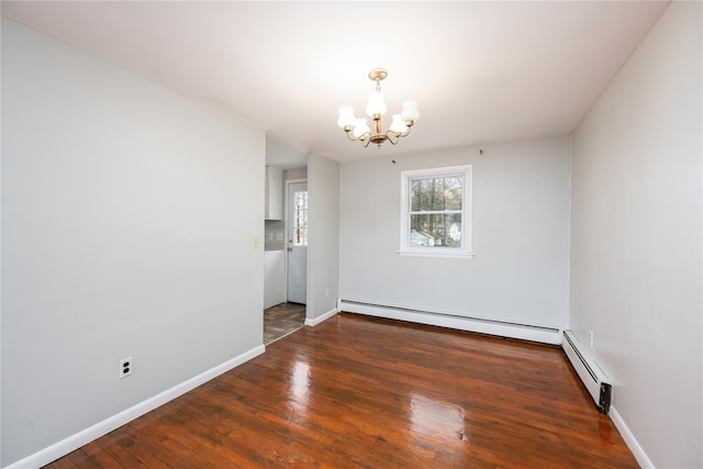 spare room featuring dark hardwood / wood-style floors, an inviting chandelier, and a baseboard heating unit