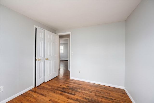 unfurnished room featuring dark hardwood / wood-style flooring and baseboard heating