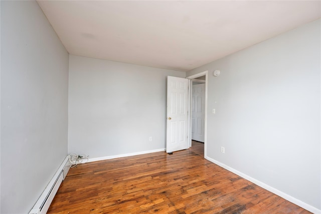 empty room with dark hardwood / wood-style floors and a baseboard heating unit