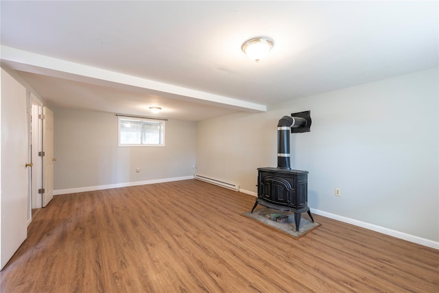 unfurnished living room featuring wood-type flooring, a wood stove, and baseboard heating