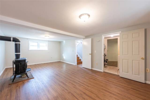 basement with a wood stove and hardwood / wood-style flooring