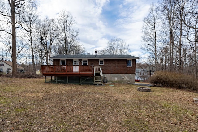 back of house featuring a lawn, a wooden deck, and a fire pit