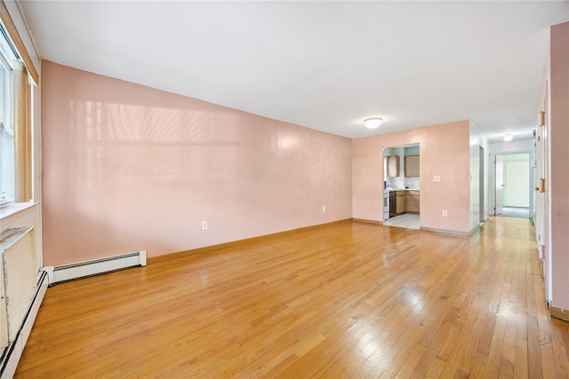 unfurnished living room with a baseboard heating unit and light hardwood / wood-style flooring