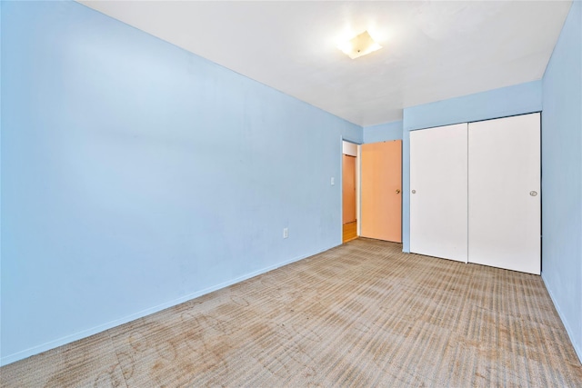 unfurnished bedroom featuring a closet and light colored carpet