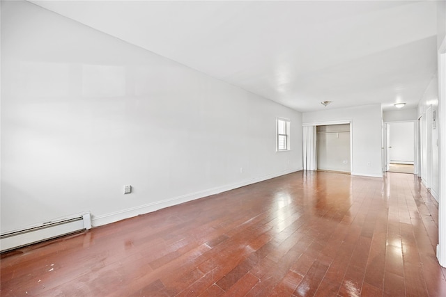 empty room with baseboard heating and hardwood / wood-style flooring