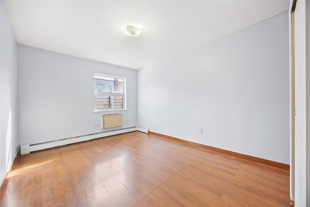 unfurnished room with hardwood / wood-style flooring and a baseboard heating unit