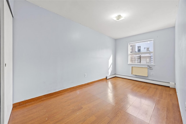 empty room with hardwood / wood-style floors and baseboard heating