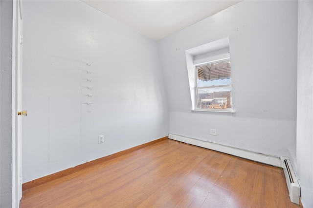 spare room featuring a baseboard radiator and hardwood / wood-style flooring