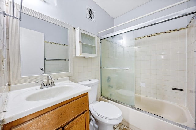 full bathroom featuring vanity, bath / shower combo with glass door, tile walls, and toilet