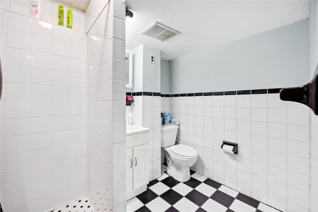 bathroom featuring walk in shower, vanity, tile walls, and toilet