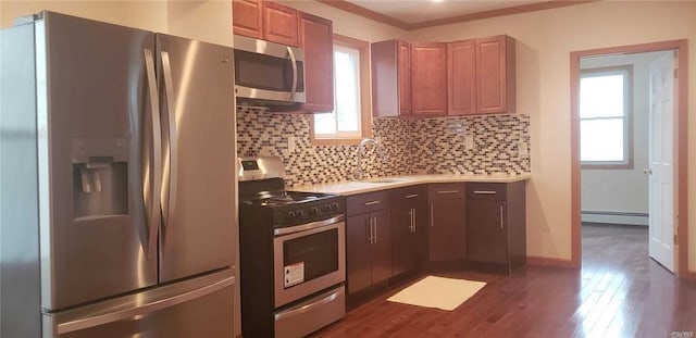 kitchen featuring tasteful backsplash, a wealth of natural light, stainless steel appliances, sink, and a baseboard radiator