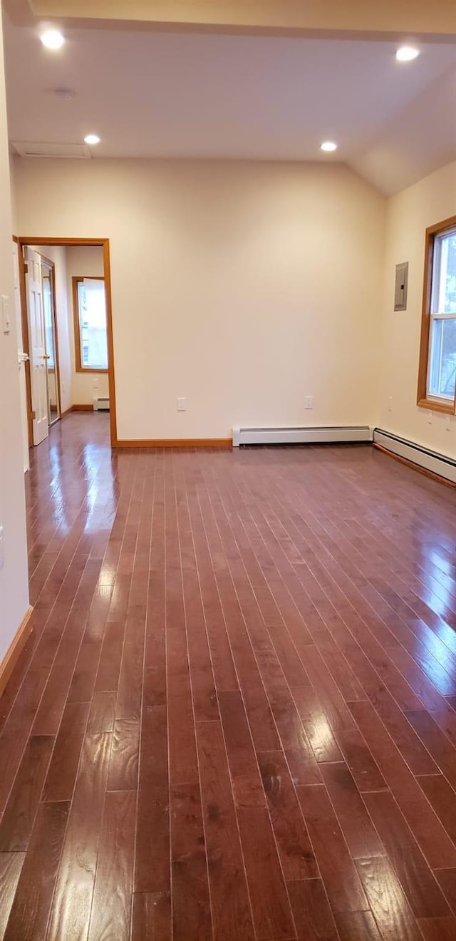 empty room featuring a wealth of natural light, dark wood-type flooring, and vaulted ceiling