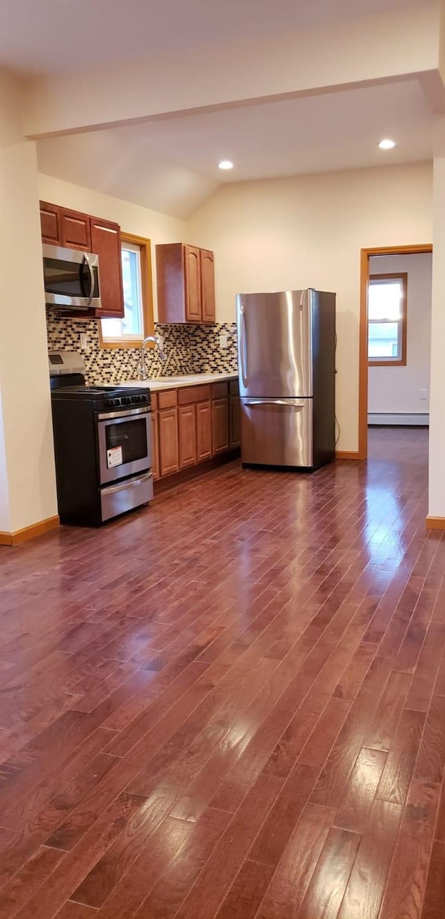 kitchen featuring decorative backsplash, stainless steel appliances, baseboard heating, dark hardwood / wood-style floors, and lofted ceiling