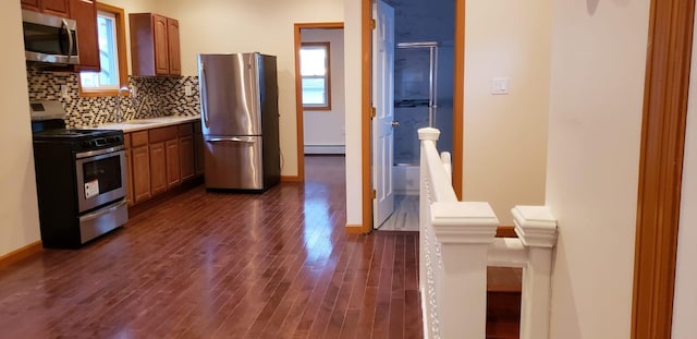 kitchen featuring backsplash, a baseboard radiator, dark hardwood / wood-style floors, and appliances with stainless steel finishes