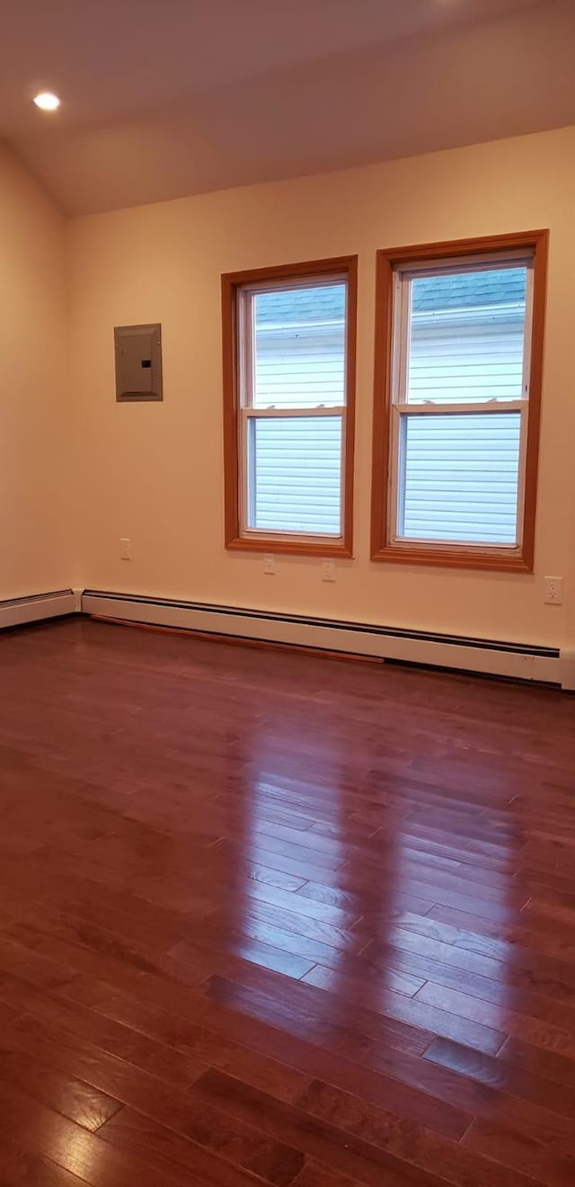 spare room with dark hardwood / wood-style flooring, electric panel, and a baseboard heating unit