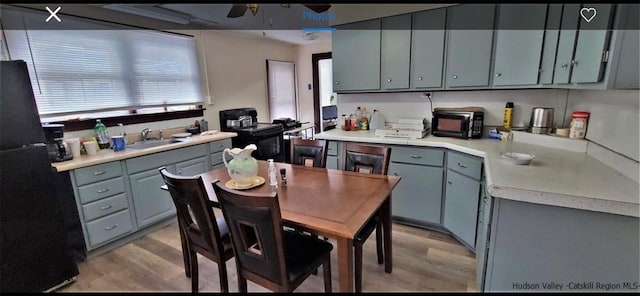 kitchen featuring light wood-type flooring, ceiling fan, sink, and black appliances