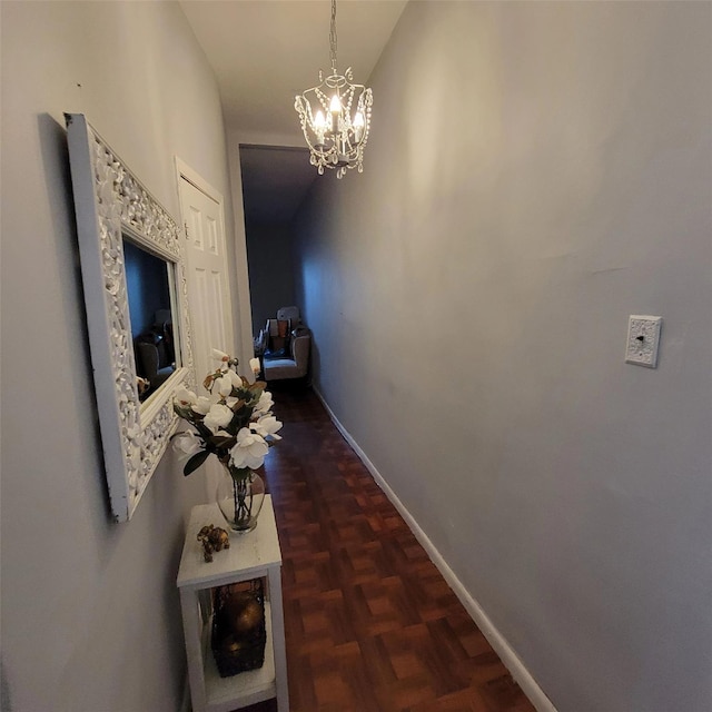 hallway with dark parquet floors and a chandelier