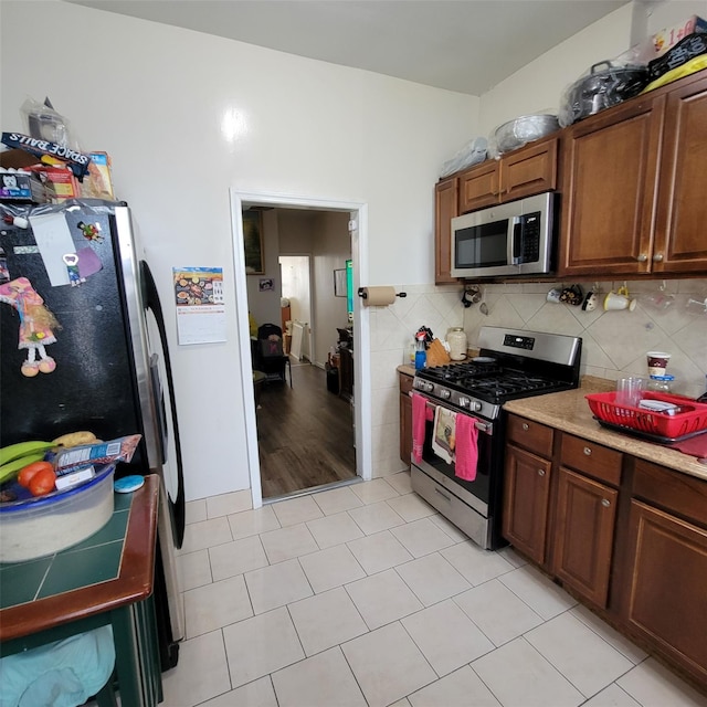 kitchen with light tile patterned flooring, appliances with stainless steel finishes, and tasteful backsplash