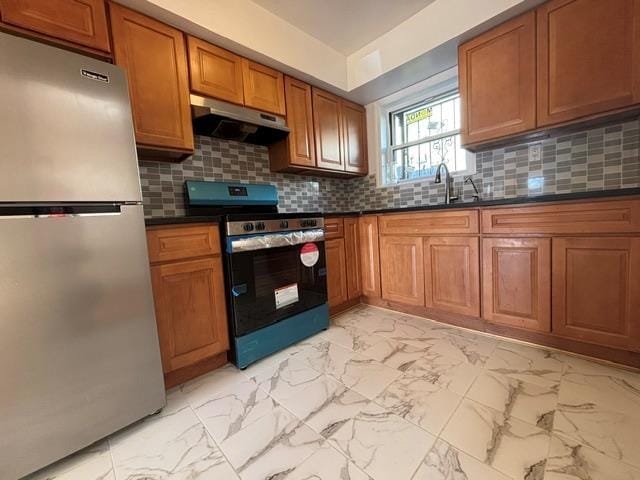 kitchen featuring tasteful backsplash, stainless steel refrigerator, sink, and black range oven