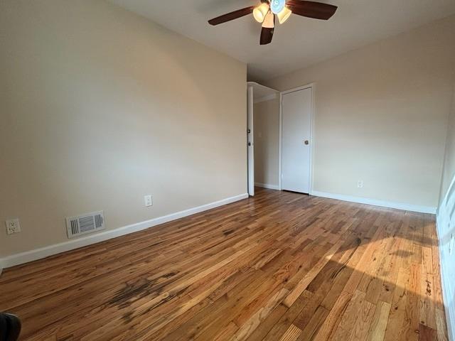 empty room with hardwood / wood-style flooring and ceiling fan