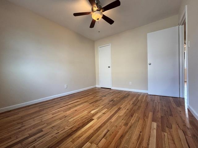 unfurnished room with ceiling fan and dark hardwood / wood-style flooring