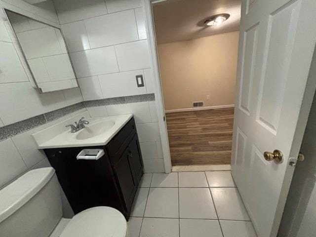 bathroom with tile patterned floors, vanity, tile walls, and toilet