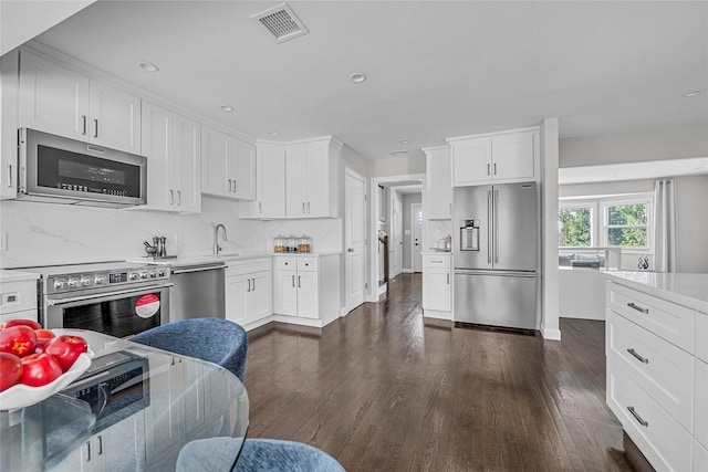 kitchen featuring decorative backsplash, dark hardwood / wood-style floors, white cabinetry, and appliances with stainless steel finishes