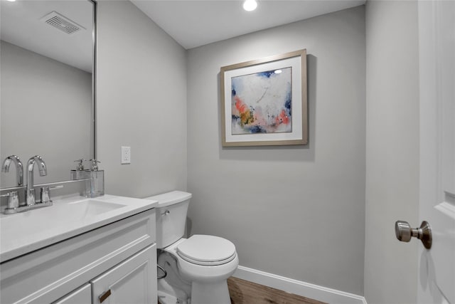 bathroom with hardwood / wood-style floors, vanity, and toilet