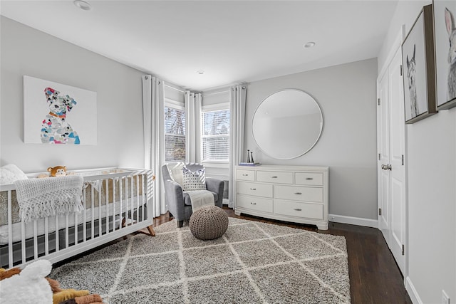 bedroom featuring dark hardwood / wood-style floors and a nursery area