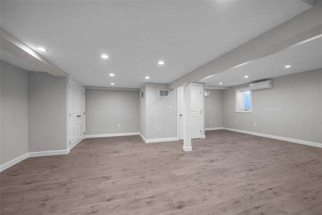 basement with light hardwood / wood-style flooring and a wall mounted AC