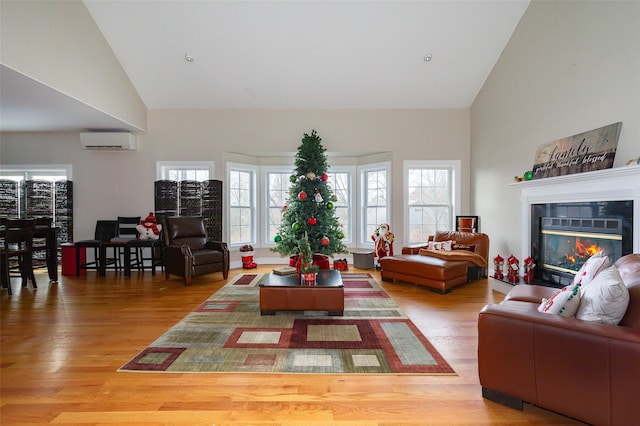 living room featuring a fireplace, high vaulted ceiling, wood-type flooring, and a wall mounted air conditioner